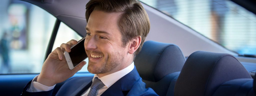 A businessman sitting in the back seat of a taxi having a conversation on his cellphone